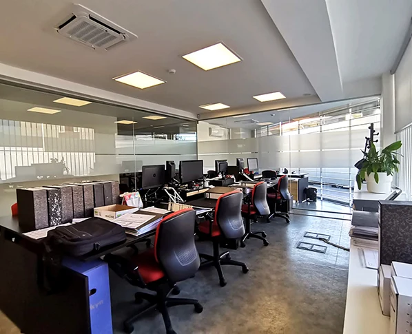Zona de trabalho do escritório Outside, com mesas e divisórias de vidro.